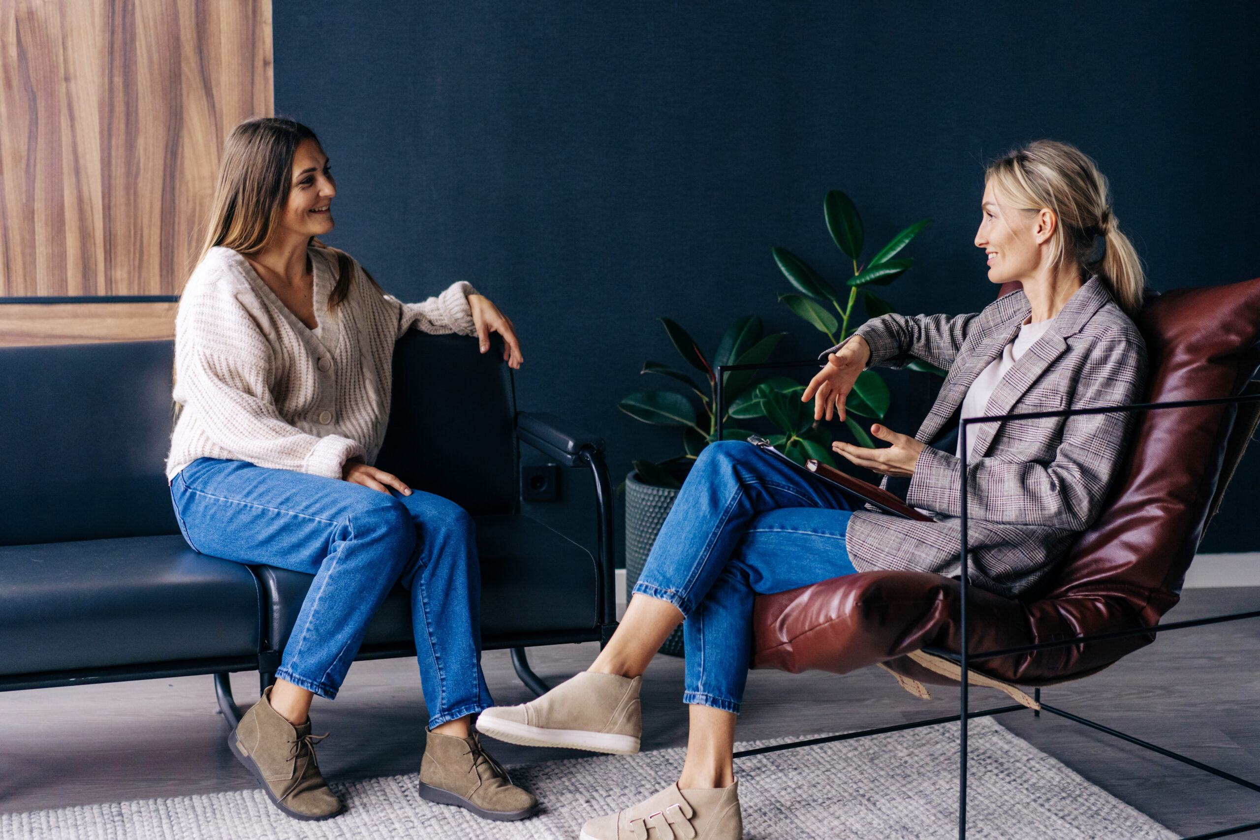 Two modern stylish women are sitting in the office discussing ideas and implementation of plans.
